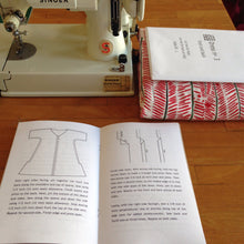 open instruction booklet, fabric, sewing pattern and sewing machine